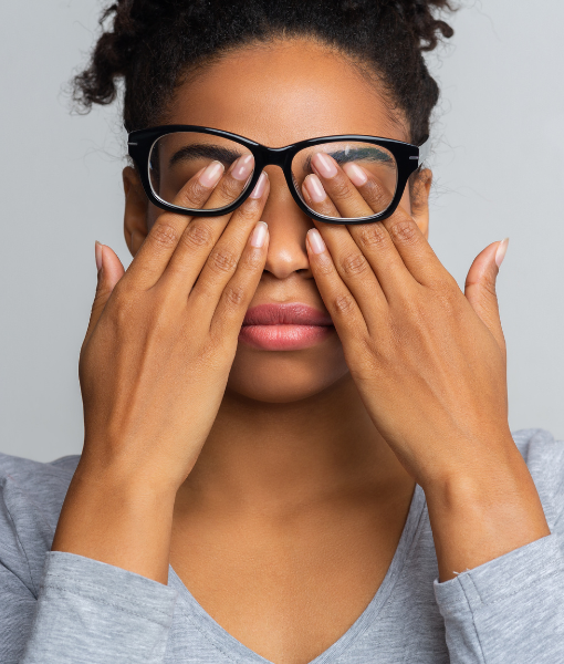 Mulher com óculos cobrindo os olhos com as mãos, representando dificuldade visual e situação que pode dar direito ao LOAS.